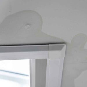 Ceiling water stains and bubbling paint above a window frame, indicating moisture intrusion and potential water damage.