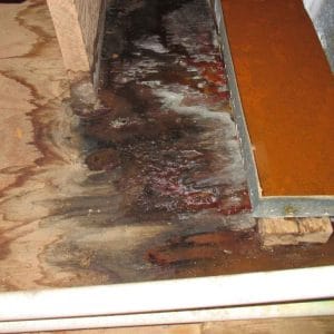 Severe water damage on wooden subfloor near HVAC unit, showing signs of black mold, rust, and prolonged moisture exposure.